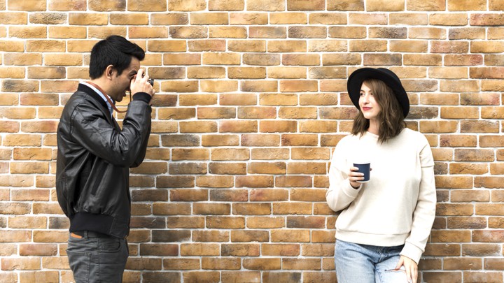 A man taking a picture of a woman wearing a hat.